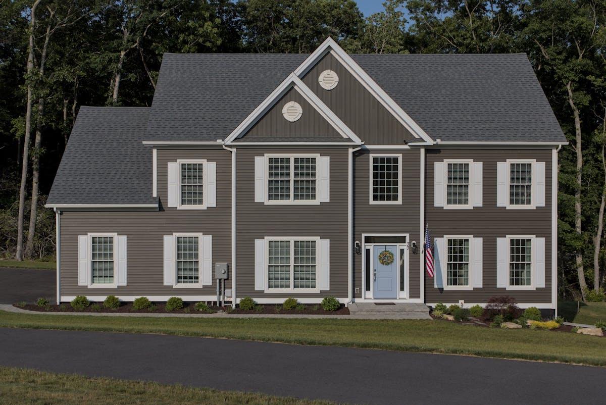 Classic colonial home with grey vinyl siding and shutters